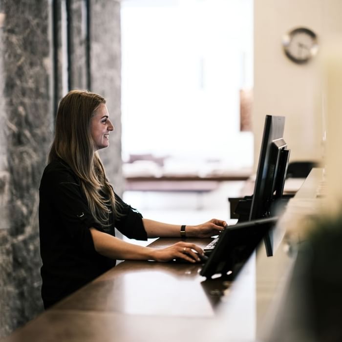 Frau arbeitet an einem Computer an der Rezeption eines Hotels.