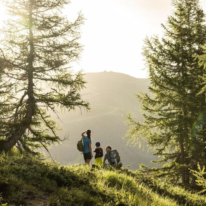Famiglia di escursionisti con zaini che si godono la vista sulle montagne al tramonto.