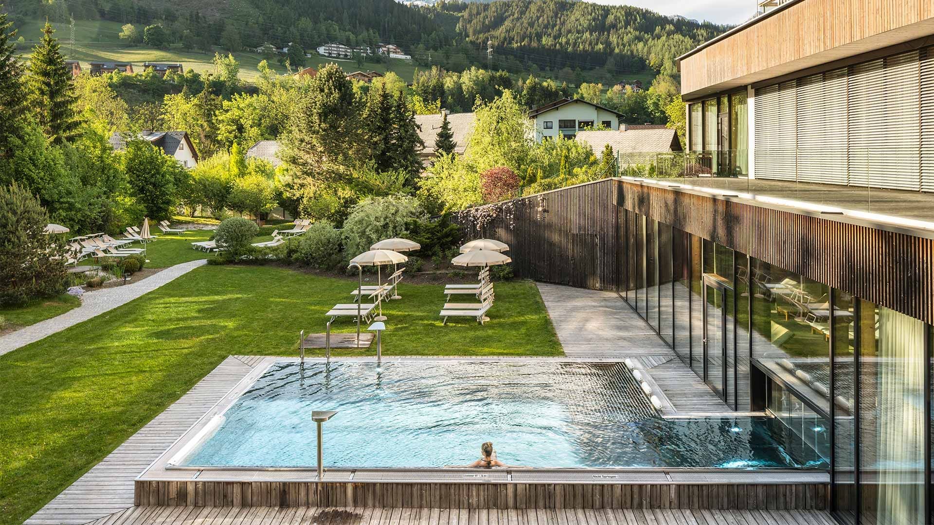 Piscina all'aperto in un resort, circondata da alberi e con vista sulle montagne.