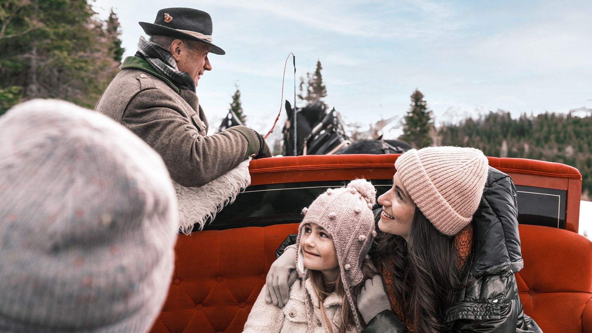 Familie genießt eine Pferdekutschenfahrt durch eine winterliche Landschaft mit Schnee und Bäumen.