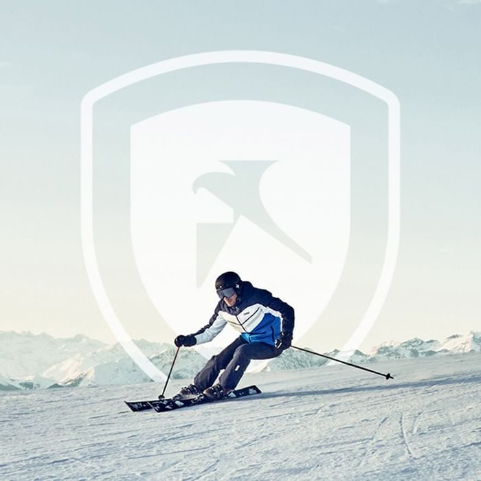 Skifahrer auf schneebedeckter Piste mit Bergpanorama und Logo im Vordergrund.