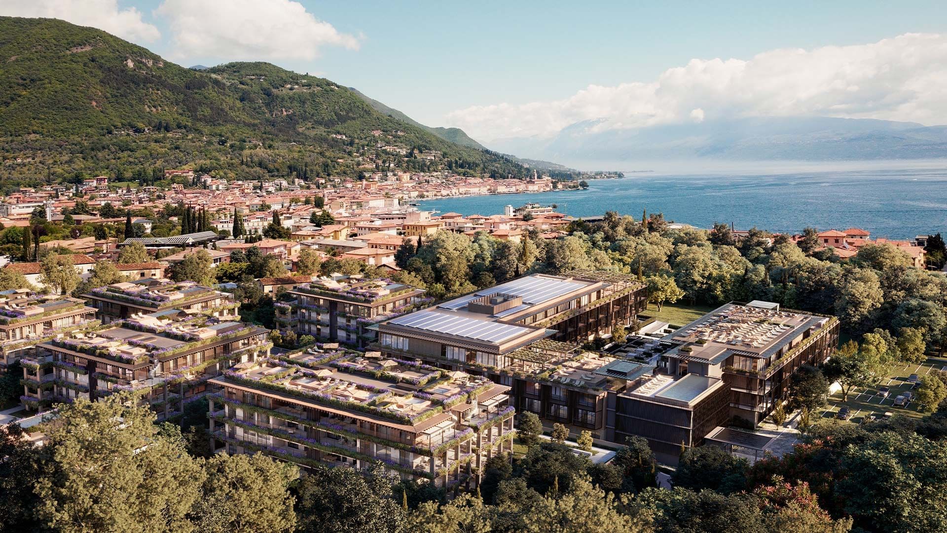 Luftaufnahme eines modernen Hotelkomplexes mit begrünten Dächern, umgeben von Bäumen und Meer.