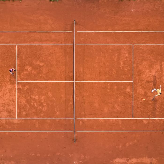Luftaufnahme eines Tennisplatzes mit zwei Spielern in den gegenüberliegenden Feldern.